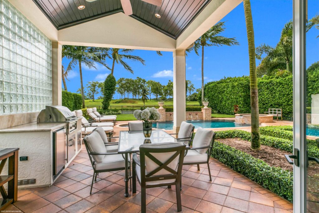 Covered loggia with summer kitchen overlooking the pool at a Palm Beach area estate